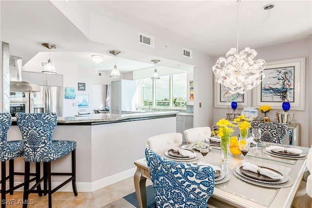 kitchen with pendant lighting, white cabinetry, stainless steel fridge, exhaust hood, and light stone counters