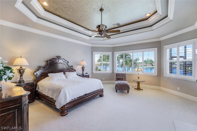 carpeted bedroom featuring ceiling fan, a tray ceiling, and crown molding