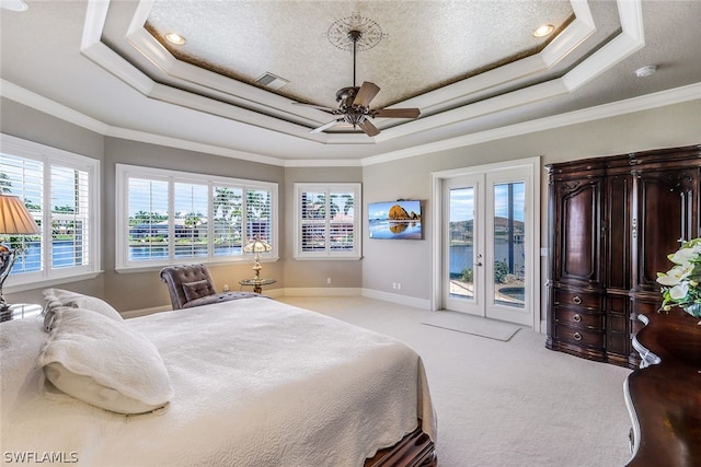 bedroom with access to outside, ceiling fan, a tray ceiling, ornamental molding, and light colored carpet