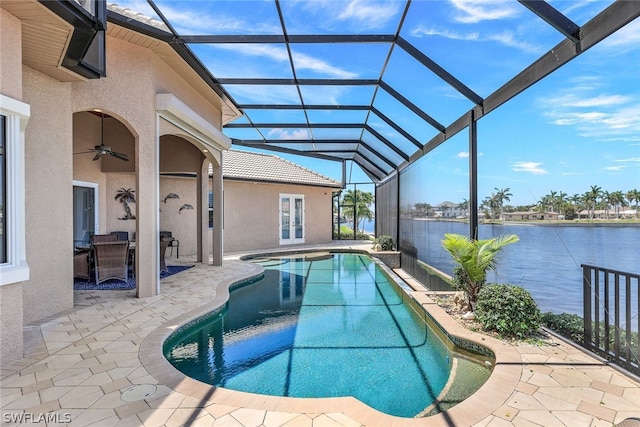 view of swimming pool featuring a patio, glass enclosure, a water view, and ceiling fan