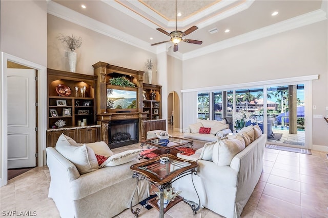 living room with a raised ceiling, ceiling fan, crown molding, and light tile floors