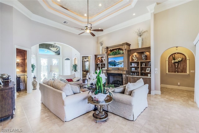 tiled living room featuring a high ceiling, ceiling fan, and crown molding