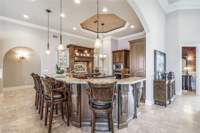 kitchen with light stone countertops, stainless steel appliances, pendant lighting, and light tile floors