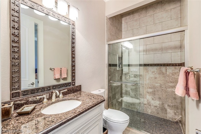 bathroom featuring a shower with shower door, oversized vanity, and toilet