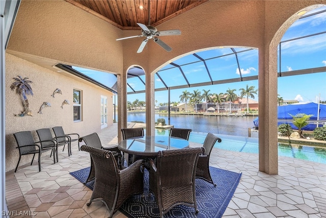 view of terrace featuring a lanai, a water view, and ceiling fan