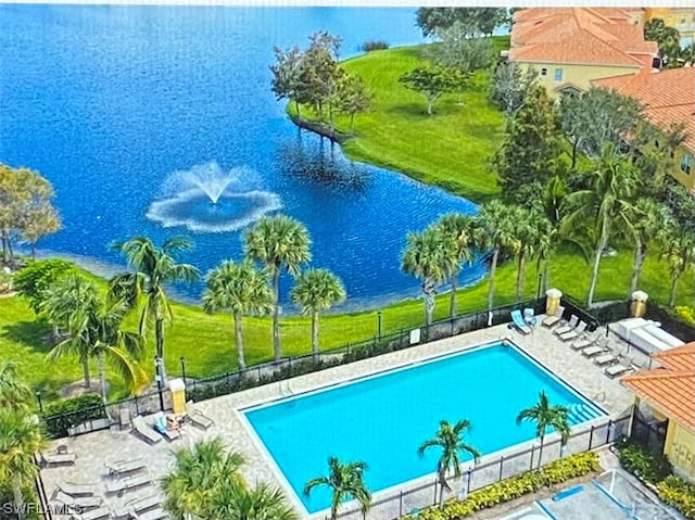 community pool with a lawn, fence, a patio, and a water view