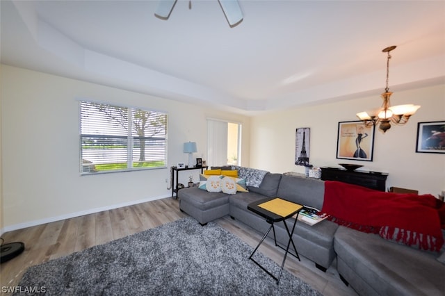 living room featuring hardwood / wood-style flooring, a notable chandelier, and a raised ceiling