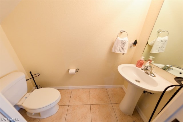 half bath with tile patterned flooring, toilet, and baseboards