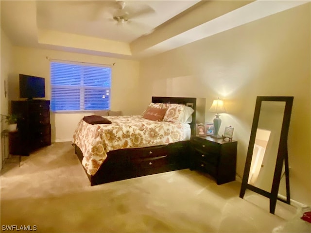 bedroom featuring light colored carpet, ceiling fan, and a tray ceiling