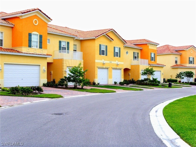 view of front of property with stucco siding, an attached garage, a tile roof, and decorative driveway