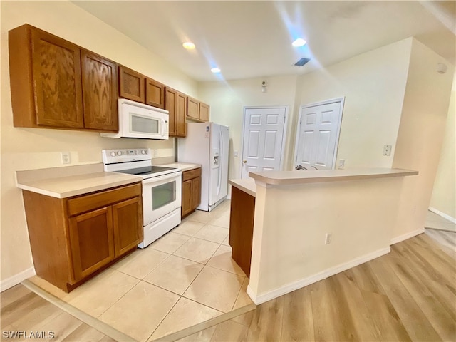 kitchen with kitchen peninsula, white appliances, and light hardwood / wood-style floors