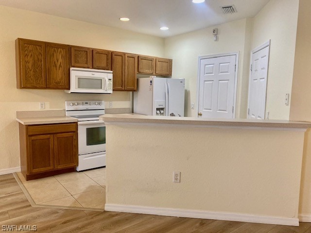 kitchen featuring kitchen peninsula, white appliances, and light hardwood / wood-style floors