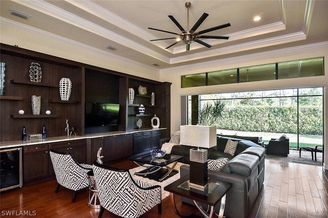 living room featuring beverage cooler, a tray ceiling, ceiling fan, and a wealth of natural light