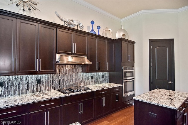 kitchen featuring light stone countertops, backsplash, gas stovetop, double oven, and light wood-type flooring