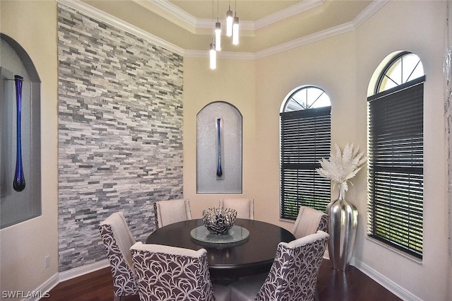 dining room with dark hardwood / wood-style floors, ornamental molding, and a towering ceiling