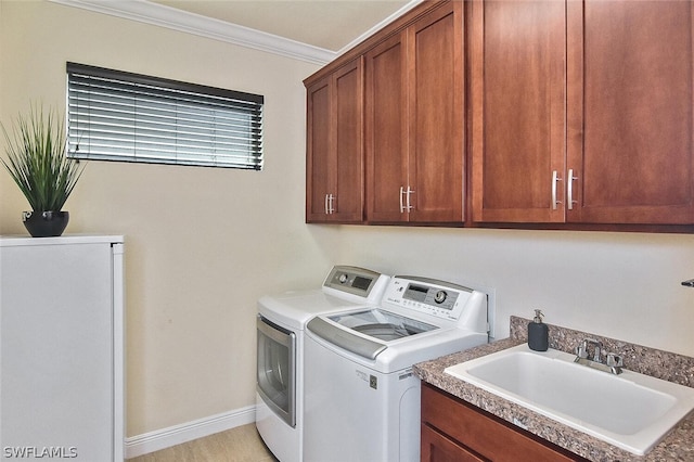 laundry room with cabinets, washer and dryer, sink, and ornamental molding