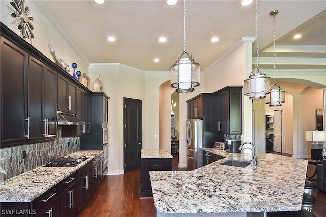 kitchen with sink, light stone counters, backsplash, dark wood-type flooring, and decorative light fixtures