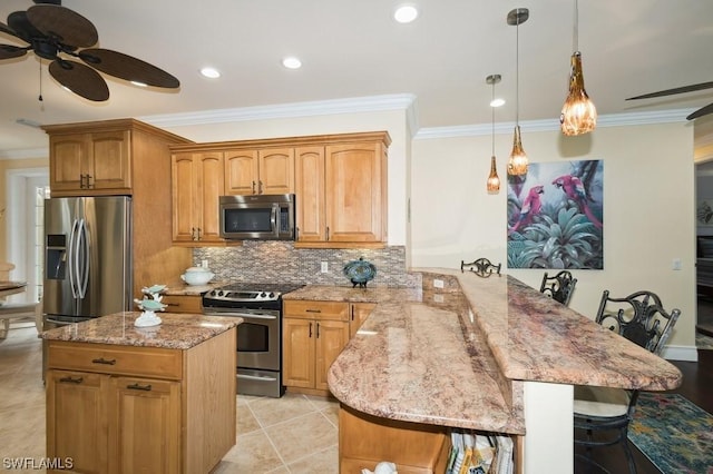 kitchen featuring appliances with stainless steel finishes, a kitchen breakfast bar, decorative light fixtures, and kitchen peninsula