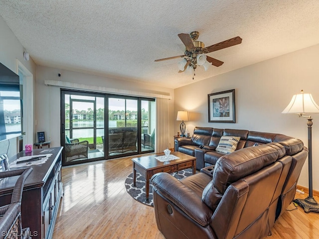 living room featuring a textured ceiling, ceiling fan, and light wood-type flooring