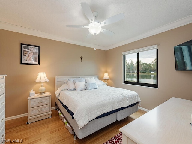 bedroom with ornamental molding, light wood-style flooring, baseboards, and a ceiling fan