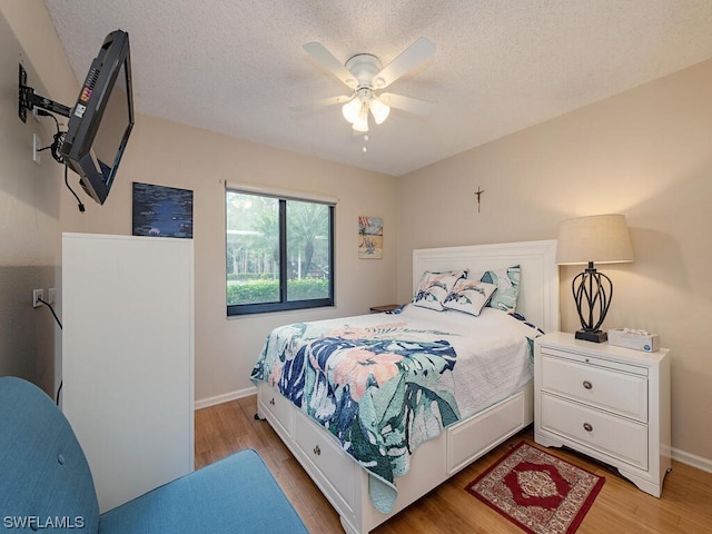 bedroom featuring light wood-type flooring, ceiling fan, a textured ceiling, and baseboards