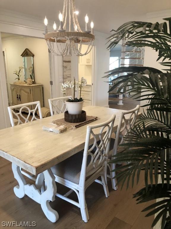 dining area with dark hardwood / wood-style floors, crown molding, and a notable chandelier