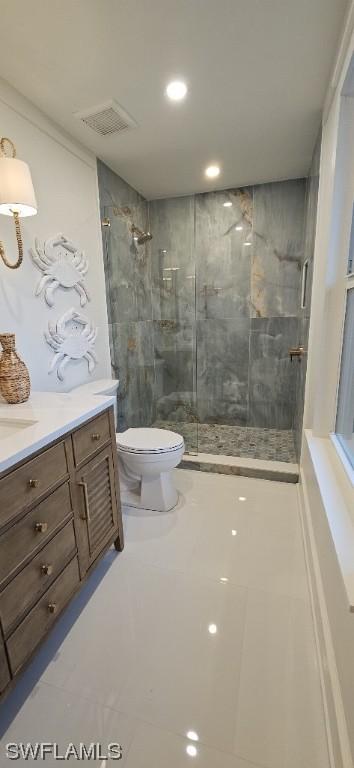 bathroom featuring tile patterned floors, toilet, a tile shower, and vanity