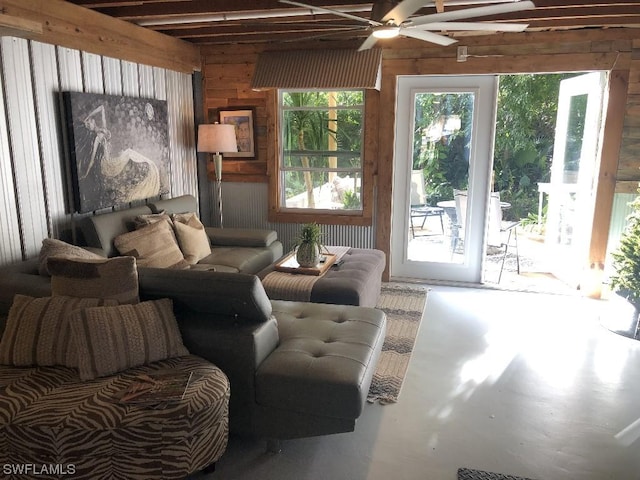 living room featuring wood walls, ceiling fan, and concrete flooring