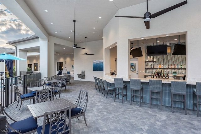 view of patio with outdoor dry bar, fence, and a ceiling fan