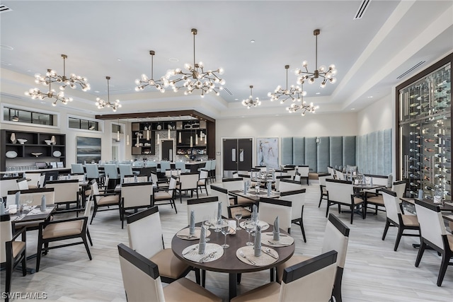 dining room with a tray ceiling, visible vents, and a high ceiling