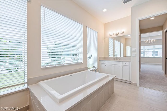 full bath with tile patterned floors, a garden tub, vanity, a chandelier, and recessed lighting