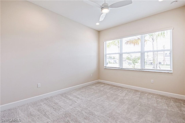 empty room featuring baseboards, a ceiling fan, light colored carpet, and a healthy amount of sunlight