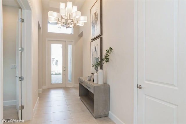 entryway featuring light tile patterned floors, a notable chandelier, and baseboards