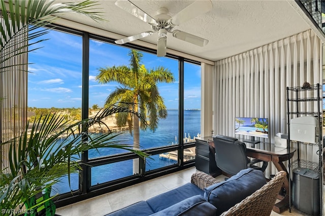 sunroom / solarium with ceiling fan and a water view