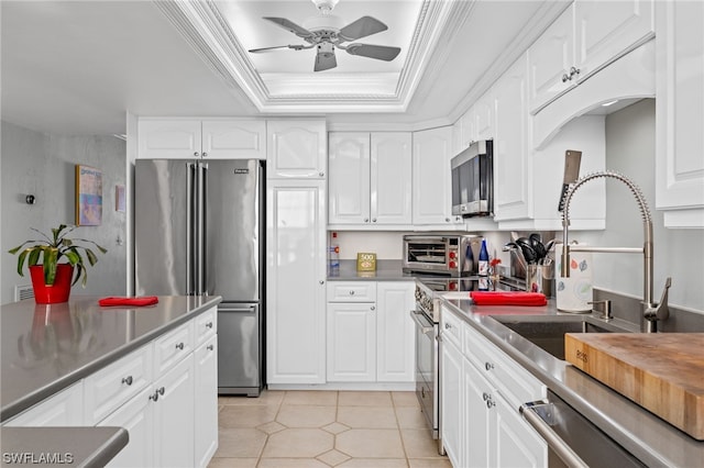 kitchen with ceiling fan, white cabinets, a raised ceiling, crown molding, and high quality appliances