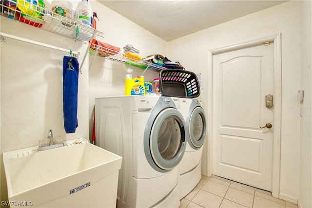 laundry area featuring light tile flooring, separate washer and dryer, and sink