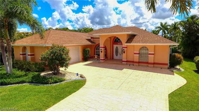 mediterranean / spanish home featuring a front lawn and a garage