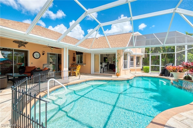 view of swimming pool featuring glass enclosure, ceiling fan, and a patio