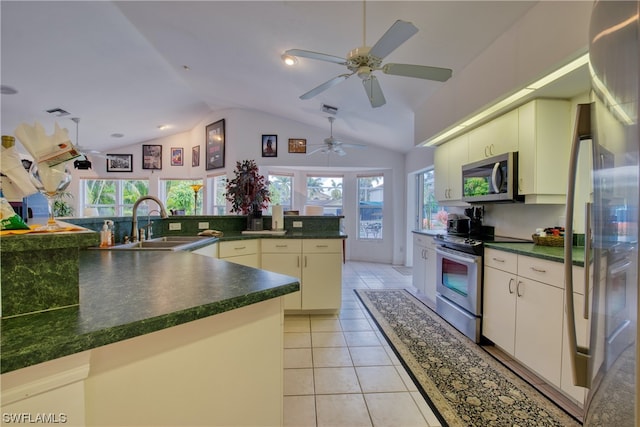 kitchen with light tile floors, vaulted ceiling, stainless steel appliances, and ceiling fan