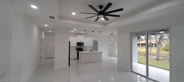 kitchen with ceiling fan, range with electric cooktop, sink, white cabinets, and a tray ceiling