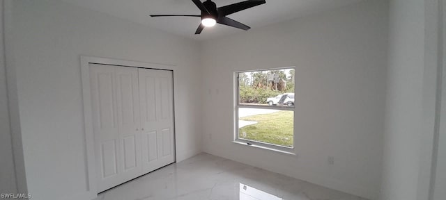 unfurnished bedroom featuring light tile flooring, ceiling fan, a closet, and multiple windows