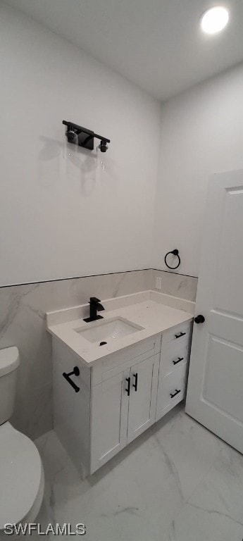 bathroom featuring vanity, tile floors, toilet, and tile walls