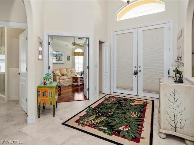 tiled foyer entrance with french doors, ceiling fan, and a towering ceiling