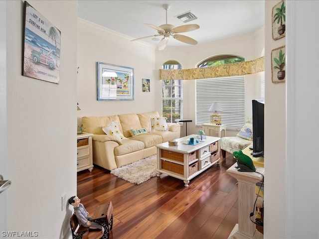 living room with crown molding, ceiling fan, and dark wood-type flooring