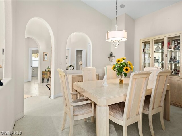 dining area featuring light carpet and high vaulted ceiling