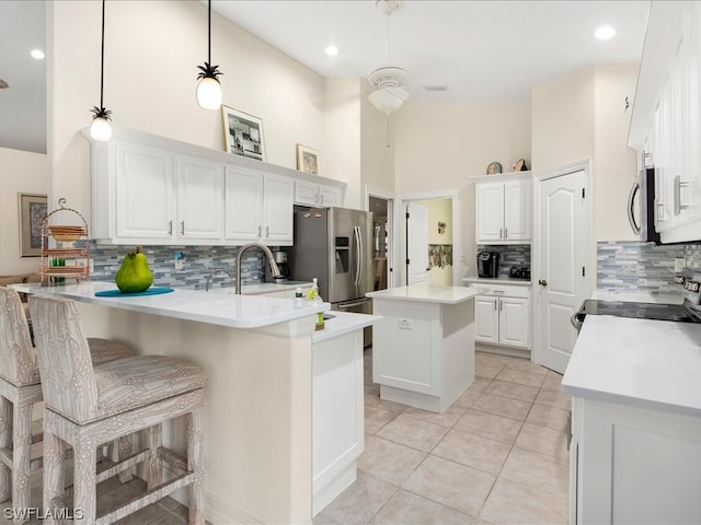 kitchen with range, backsplash, ceiling fan, white cabinets, and pendant lighting