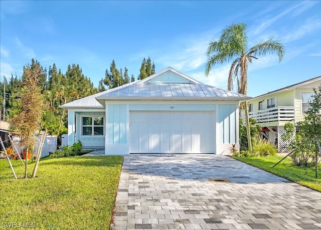 ranch-style home featuring a front yard, a standing seam roof, an attached garage, decorative driveway, and metal roof