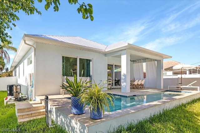 rear view of property with a patio area, fence, a fenced in pool, and metal roof