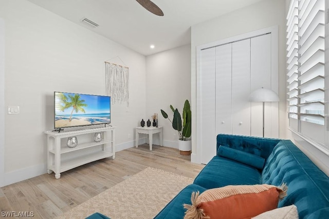 living room featuring ceiling fan, visible vents, baseboards, and wood finished floors