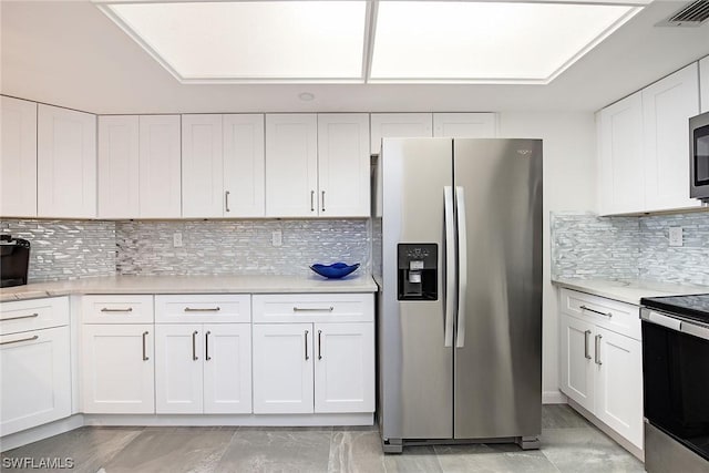 kitchen with tasteful backsplash, white cabinets, and appliances with stainless steel finishes